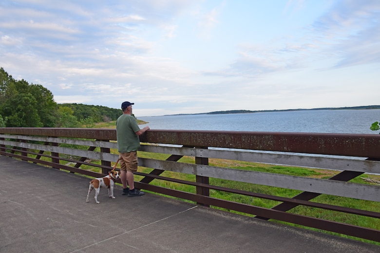 A man walking his dog on the Volksweg Trail stops to look out at Lake Red Rock near Pella, Iowa.