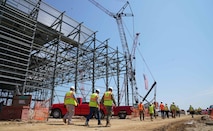 Naval Facilities Engineering Command (NAVFAC) Washington personnel celebrate the raising of the final structural steel beam of the new Executive Airlift Hangar Complex at Joint Base Andrews along with representatives from Air Force District of Washington, Clark Construction Group LLC and other trade partners, Aug. 5.