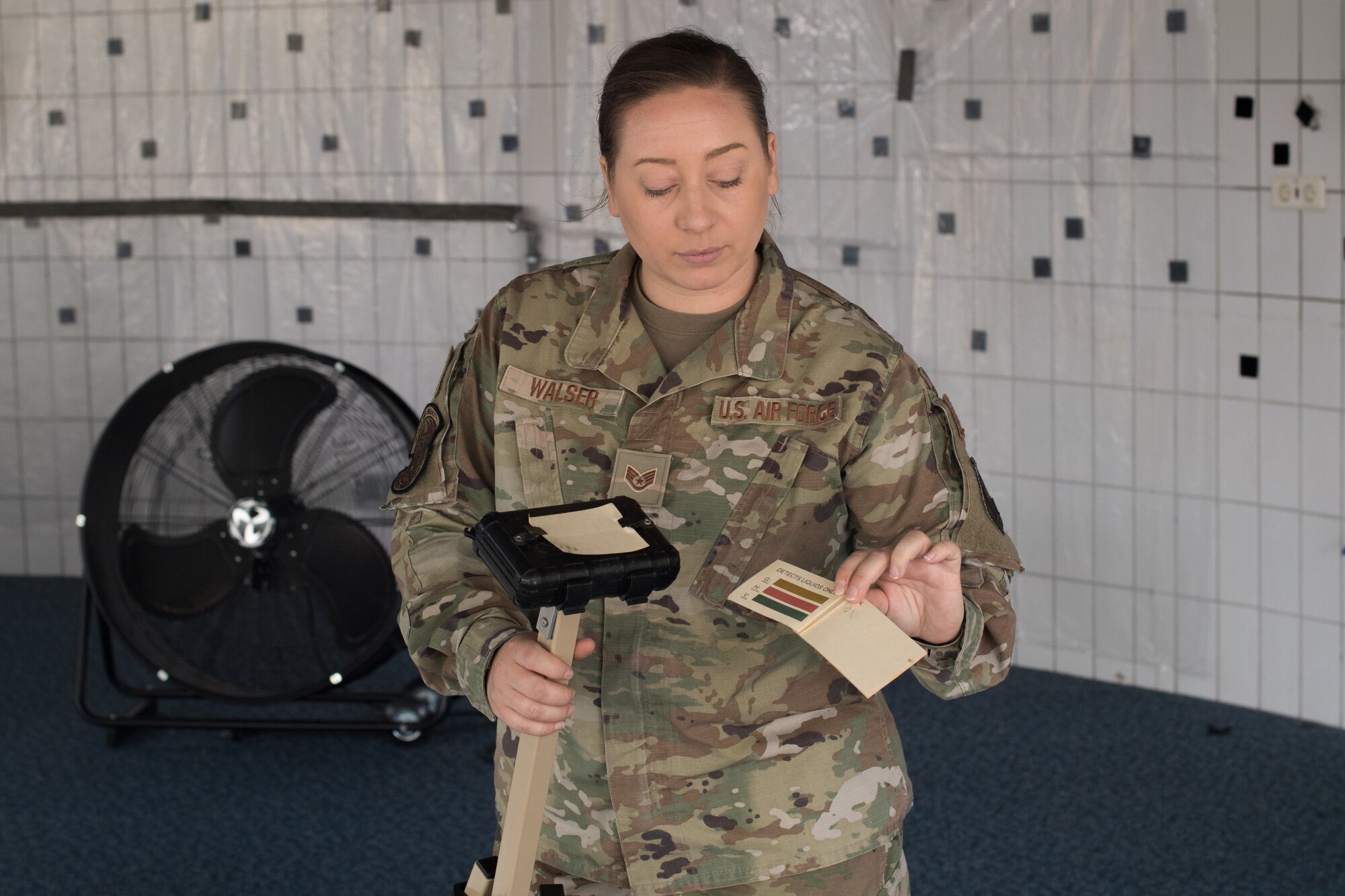 An Airman holding a stanchion and chemical detection paper.