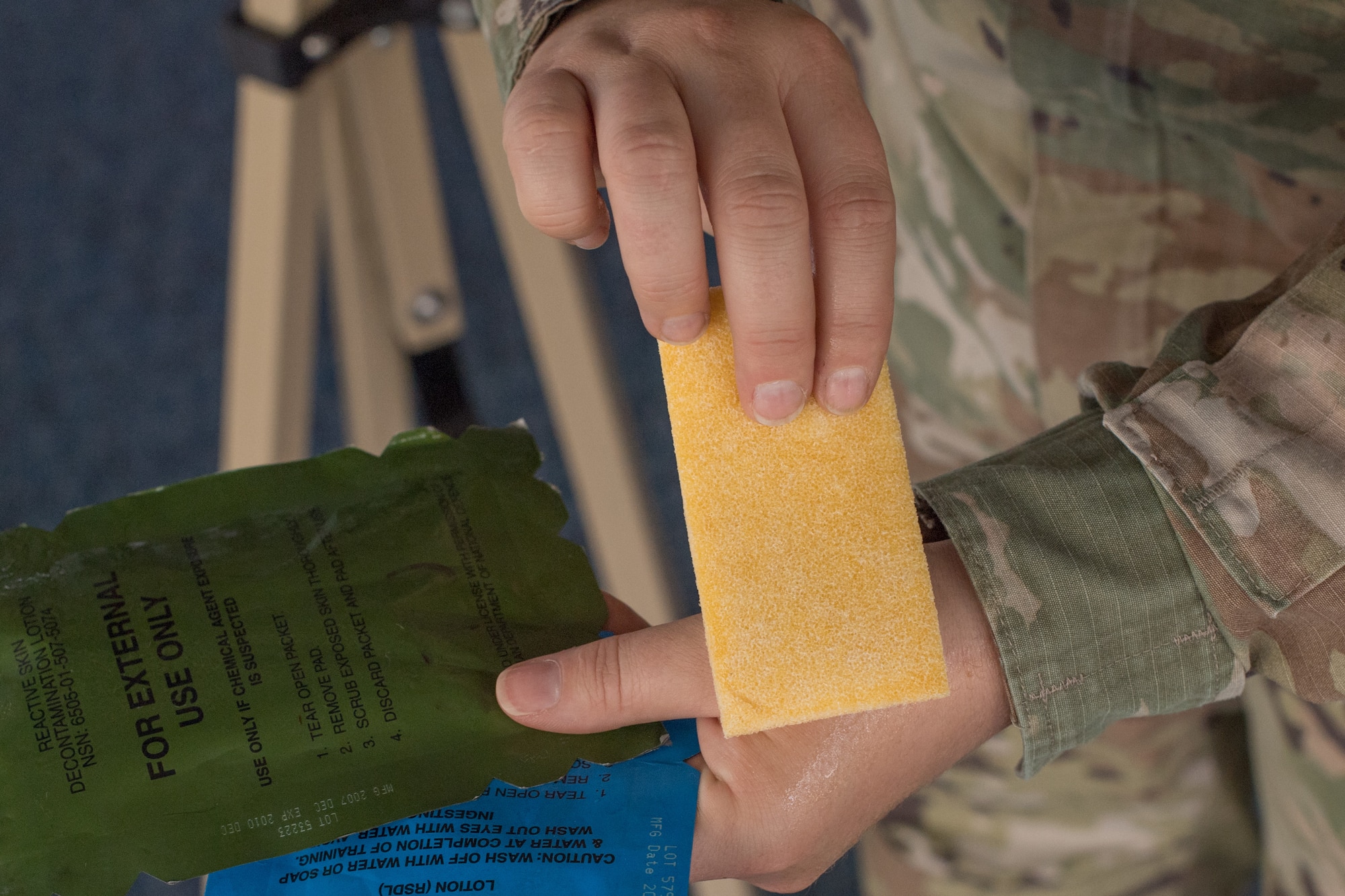 A close-up of the hands of an Airman holding a decontamination sponge.