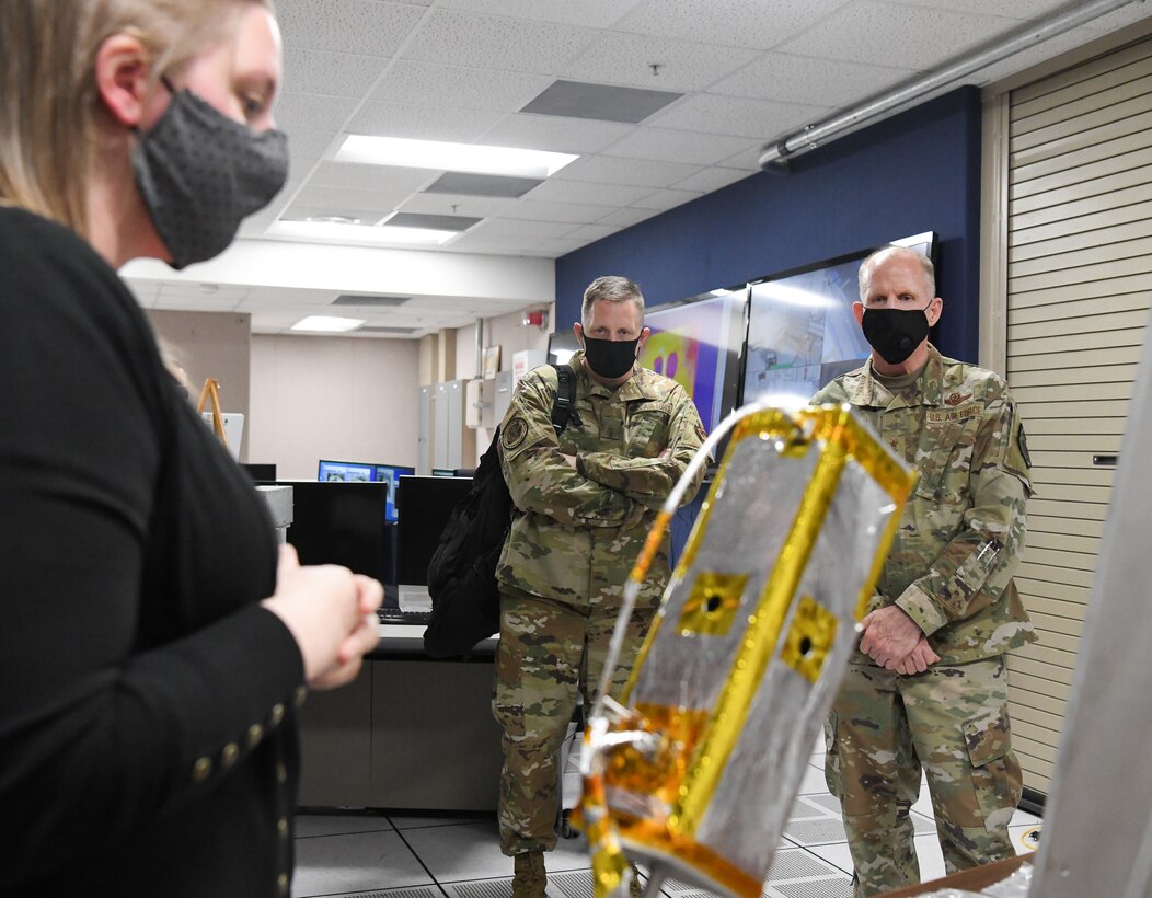 Lindsay Anderson, an Arnold Engineering Development Complex (AEDC) test engineer, briefs Vice Chief of Staff of the Air Force Gen. Stephen Wilson, right, and Brig. Gen. William Henry Kale, Director of Civil Engineers at Headquarters Air Force, during their visit to Arnold Air Force Base, Tenn., Aug. 11, 2020. In the foreground is a CubeSat, a small research satellite. (U.S. Air Force photo by Jill Pickett)