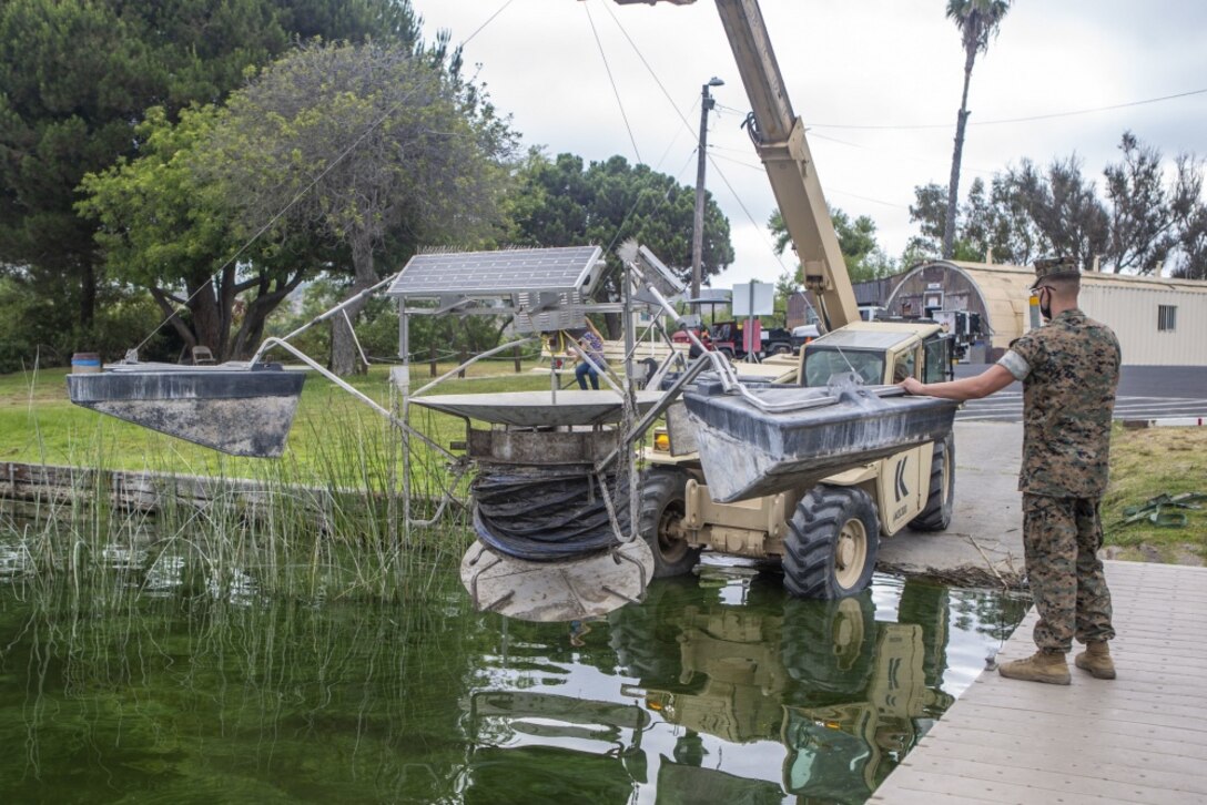 U.S. Marines with 7th Engineer Support Battalion, 1st Marine Logistics Group, and members of the Resource Management Branch, Environment Security, Marine Corps Base Camp Pendleton, lower a solar-powered water circulator into Lake O'Neill on Camp Pendleton, California, Aug 4, 2020. The circulators help prevent algal growth and improve oxygenation by mixing and aerating water throughout the lake. Camp Pendleton’s Resource Management Branch performed maintenance on three units, then returned them into the lake with assistance from 7th ESB. (U.S. Marine Corps photo by Lance Cpl. Drake Nickels)