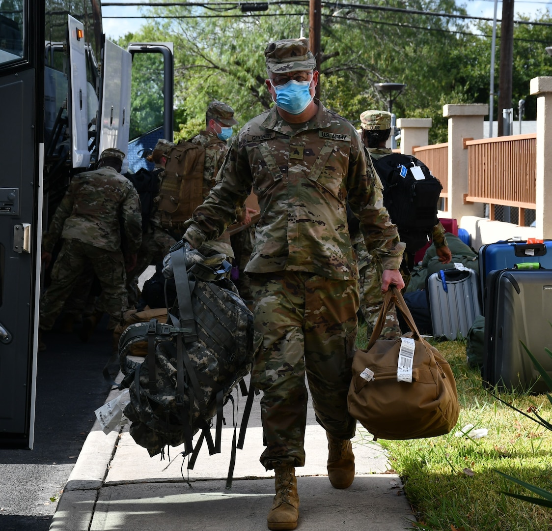 Soldier carrying bags from bus.