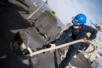 Sailors stand on the front deck of a ship.