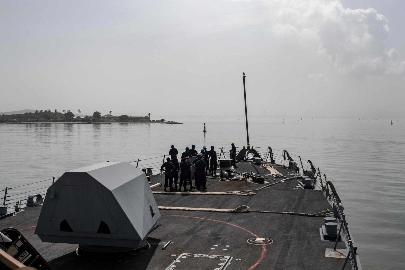 Sailors stand on the front deck of a ship.