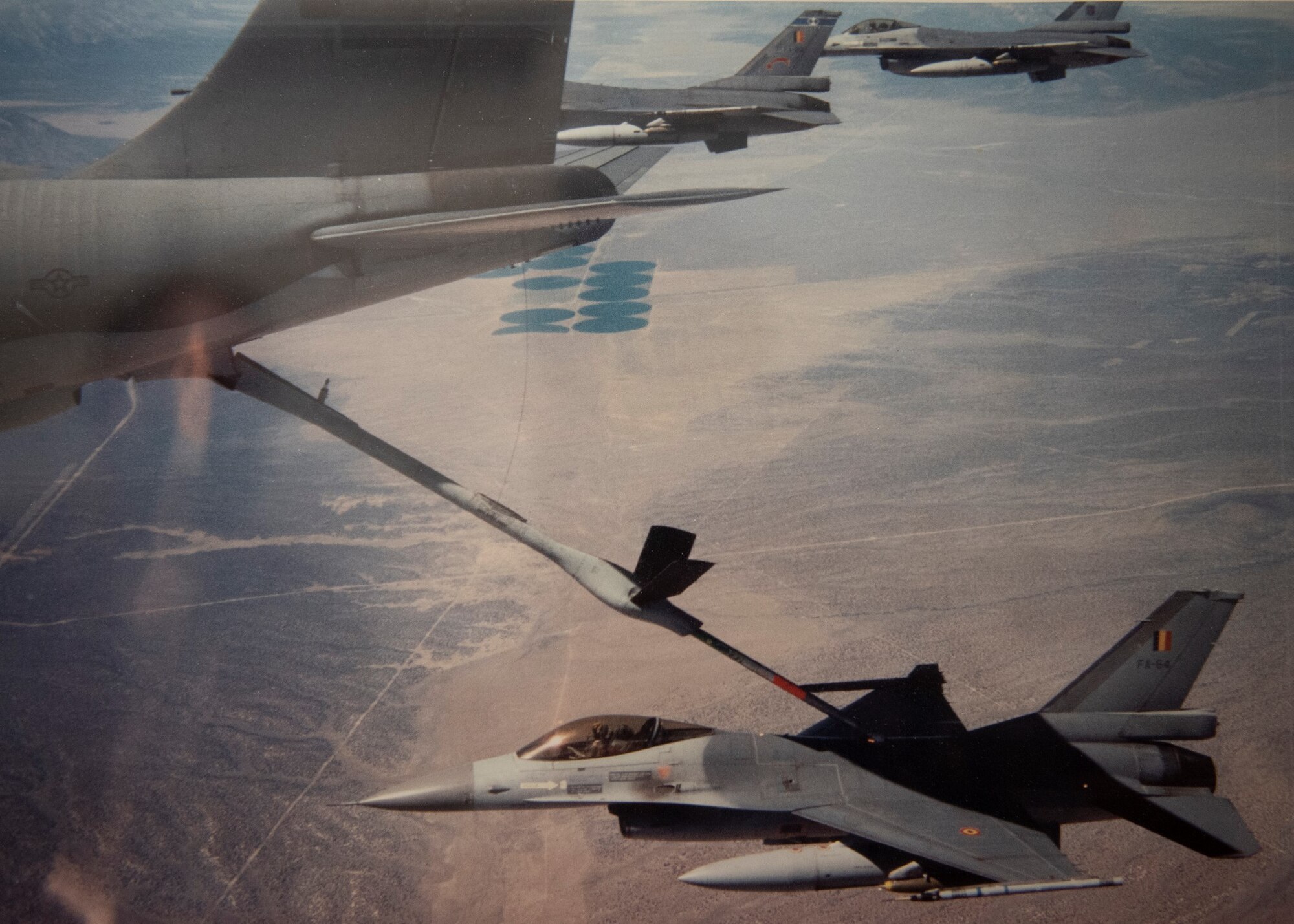 An F-16 gets refueled while flying in formation with two other F-16s.