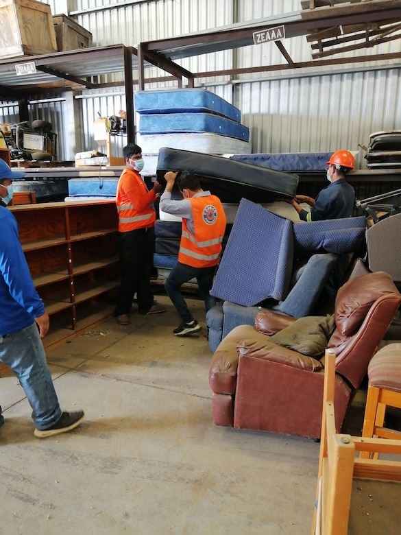 Honduran Disaster Response Agency employees and a warehouse worker for 407th Army Field Support Brigade work together July 15 at Soto Cano Air Base to carry mattresses and other humanitarian aid items provided to Honduras during the COVID-19 pandemic.