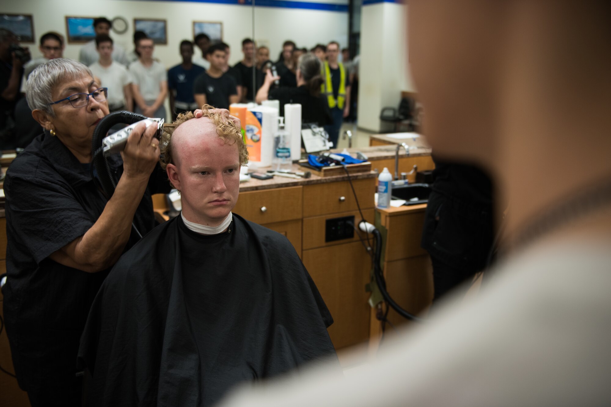 Airmen getting head shaved by civilian barber