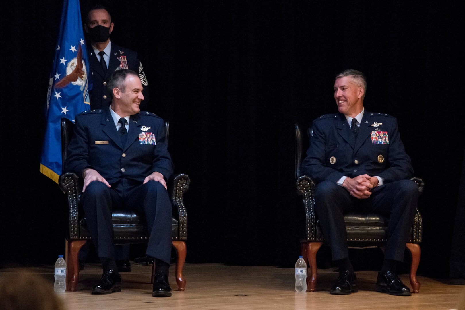 photo of Maj. Gen. Toth an Maj. Gen. Craige sitting on stage and laughing during the change of command ceremony.