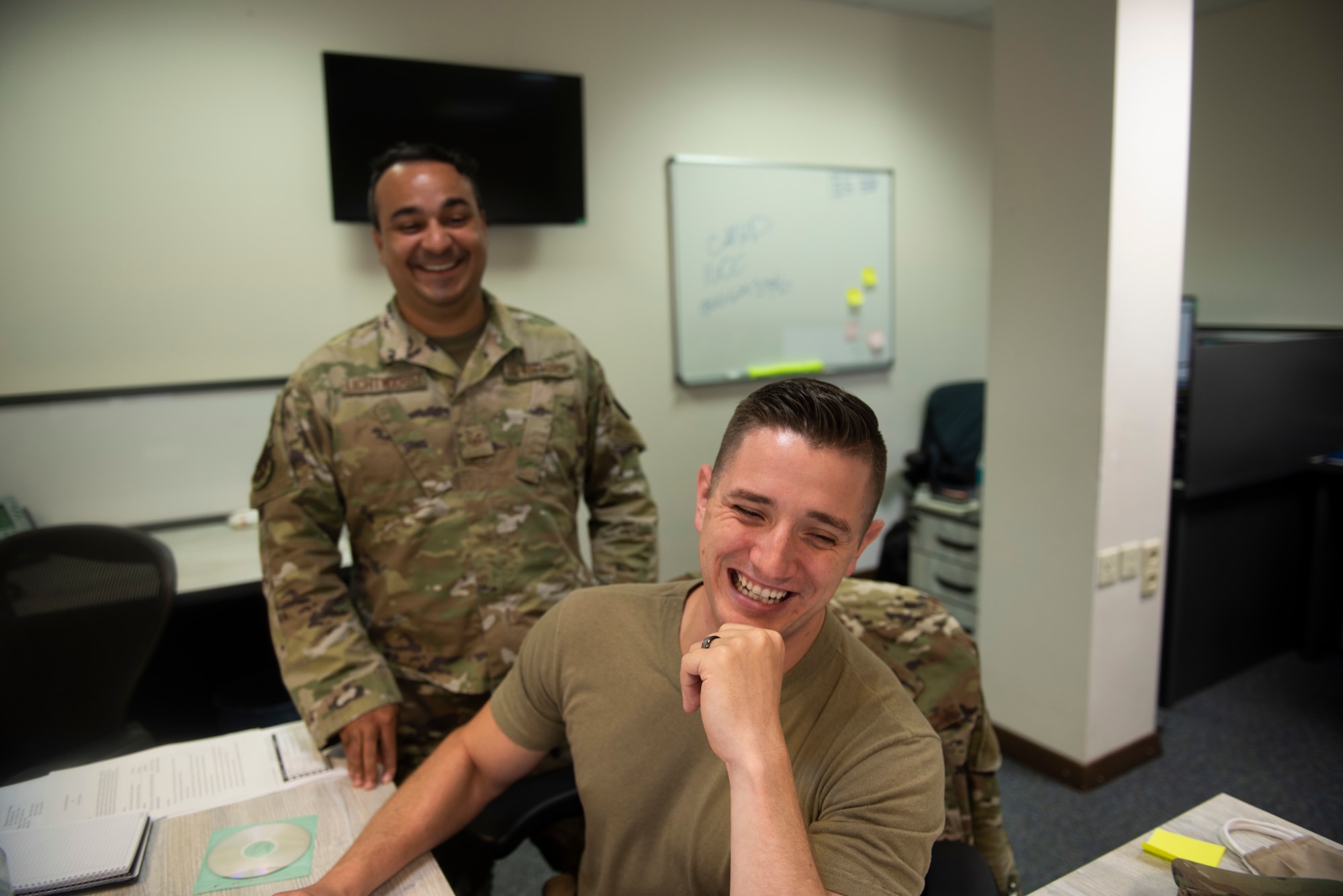 Photo of two Airmen working at a desk.