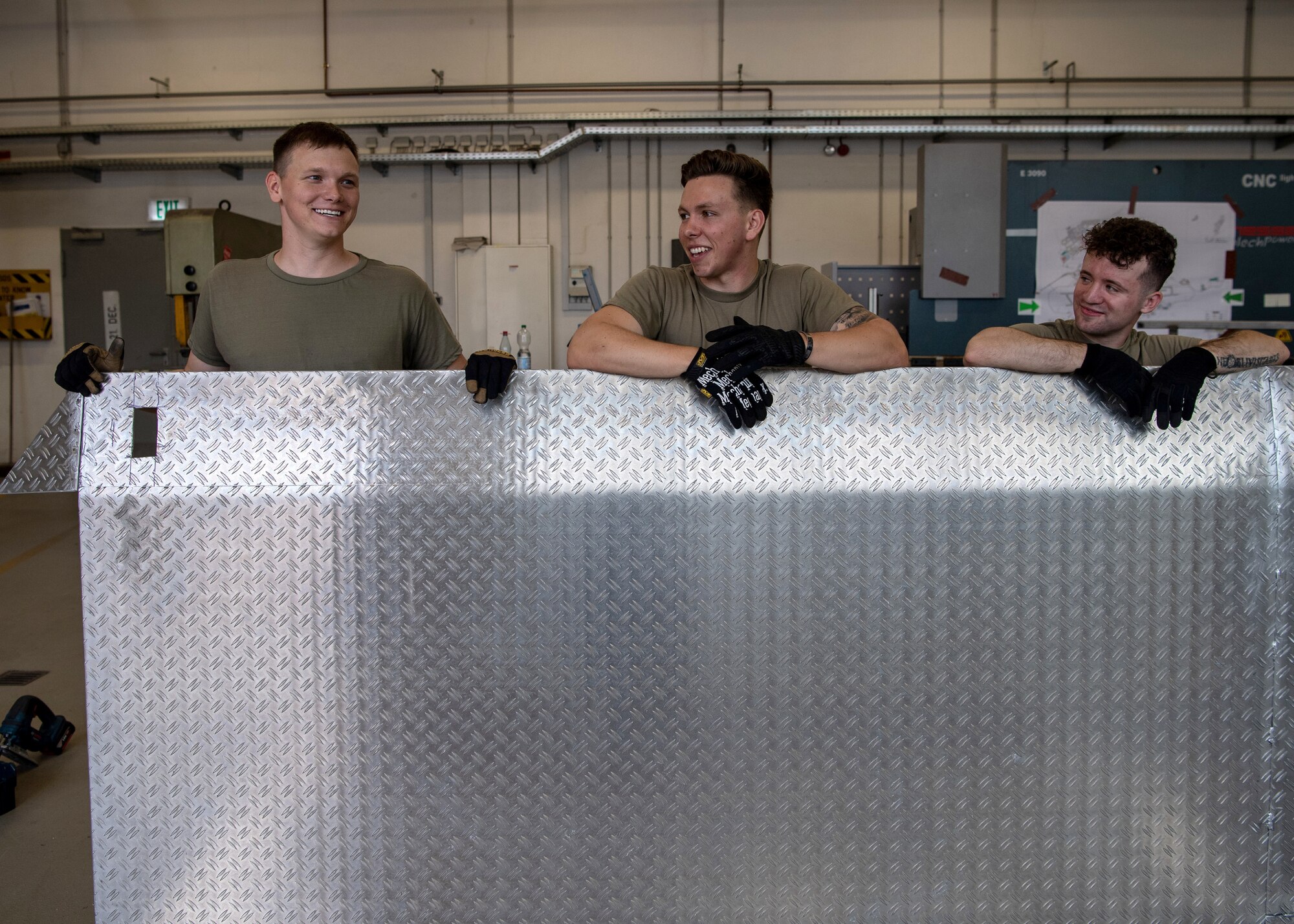 U.S. Air Force Senior Airman Dyllan Greer, Airman 1st Class Tyler Sellitto and Airman 1st Class Austen Campbell, structural journeymen from the 786th Civil Engineer Squadron, pose for a photo behind their handmade bio containment unit ramp at Ramstein Air Base, Germany, Aug. 10, 2020.