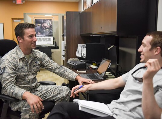 A man in a uniform talks to another man.