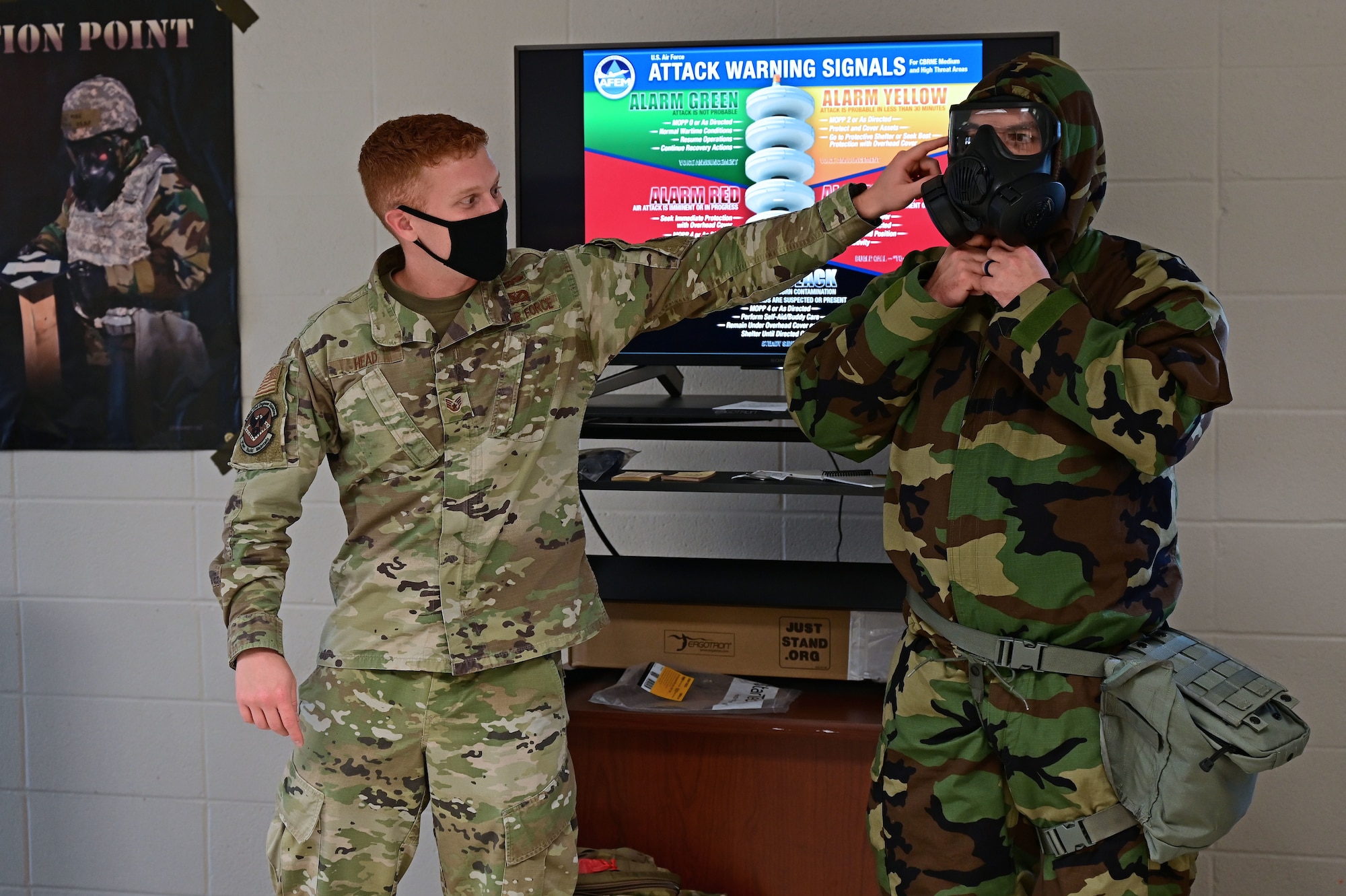 Airmen demonstrate the proper way to put on a gas mask.