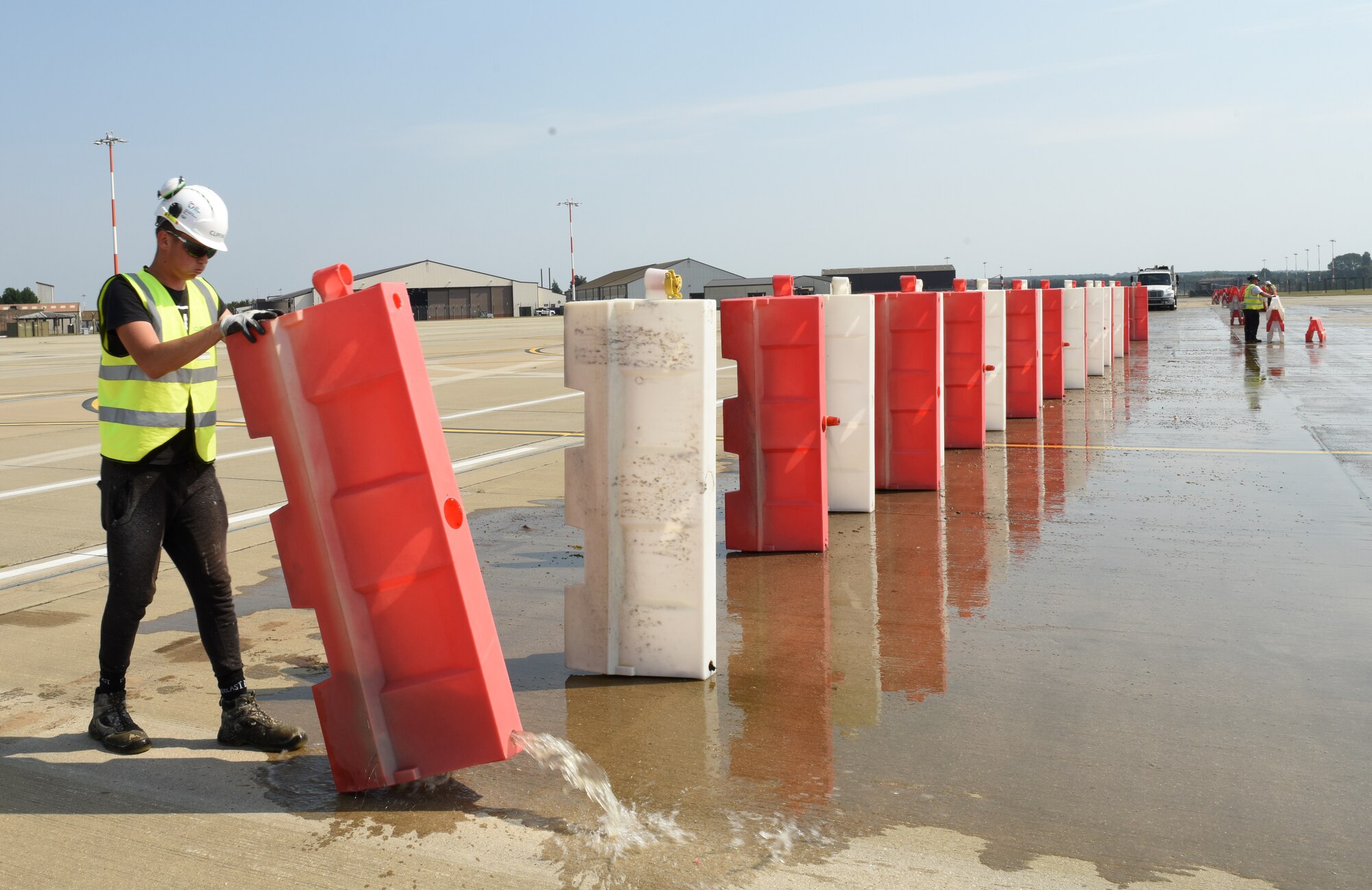 A civilian contractor removes water barriers from the newly expanded F-15E parking ramp at Royal Air Force Lakenheath, England, Aug. 10, 2020. The ramp expansion facilitates construction of new infrastructure for the F-35A Lightning II arriving in late 2021.  (U.S. Air Force photo by Airman 1st Class Rhonda Smith)