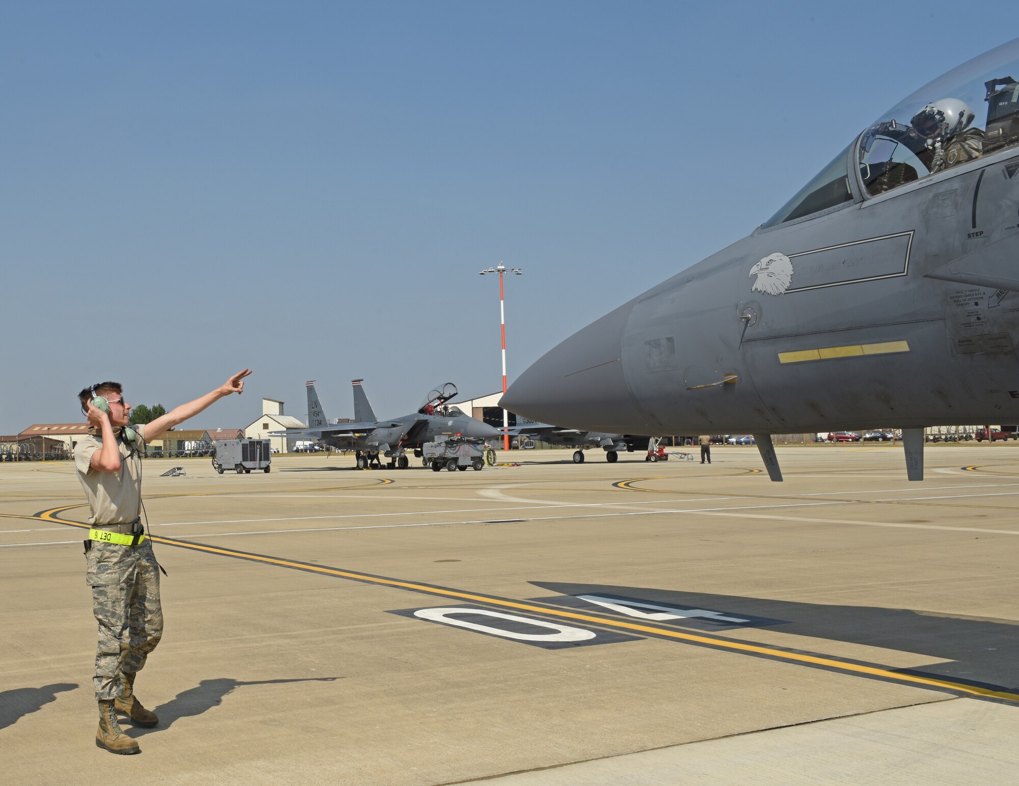 A 48th Fighter Wing crew chief marshalls an F-15E Strike Eagle onto a newly expanded parking ramp at Royal Air Force Lakenheath, England, Aug. 12, 2020. The ramp consolidates F-15E Strike Eagle operations for the two squadrons, shortens transit times and maintenance operations, and improves mission efficiency. (U.S. Air Force photo by Airman 1st Class Rhonda Smith)