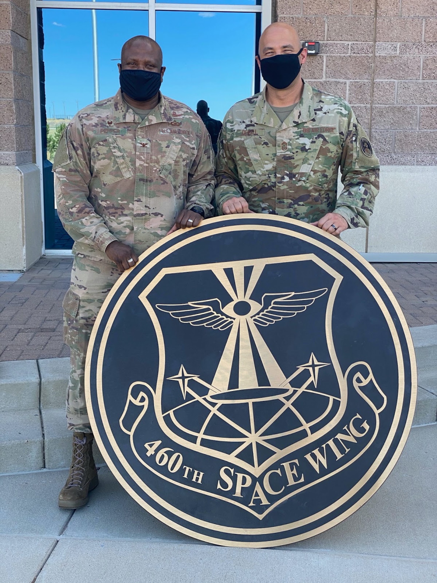 Col. Devin Pepper, Buckley Garrison commander, and Chief Master Sgt. Robert Devall, Buckley Garrison command chief, pose for a photo with the 460th Space Wing sign at the Headquarters building on Buckley Air Force Base, Colo., August 7, 2020.  The sign was taken down, along with the other 460th Space Wing signs and shields to mark “the end of an era.” The 460th was deactivated and Buckley Garrison was activated during a virtual ceremony on July 24. (U.S. Air Force photo by Staff Sgt. Jessica Kind)