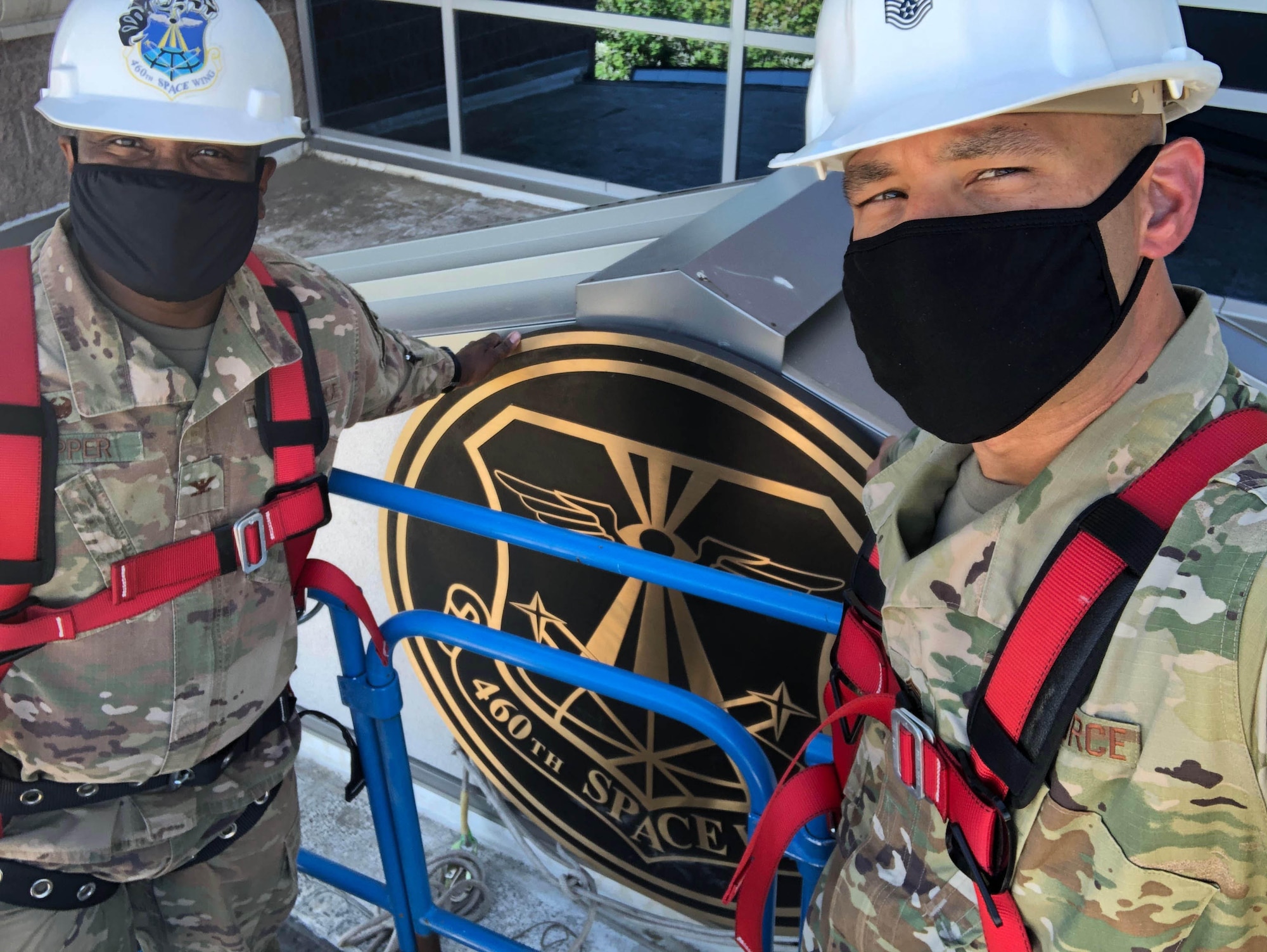 Col. Devin Pepper, Buckley Garrison commander, and Chief Master Sgt. Robert Devall, Buckley Garrison command chief, pose for a selfie prior to the removal of the 460th Space Wing sign on the Headquarters building at Buckley Air Force Base, Colo., August 7, 2020.  The sign was taken to the historian for historical purposes after it was taken down, along with the other 460th Space Wing signs and shields. The 460th was deactivated and Buckley Garrison was activated during a virtual ceremony on July 24. (U.S. Air Force photo by Staff Sgt. Jessica Kind)