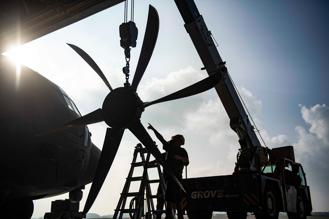 Airmen work on an aircraft’s propeller.