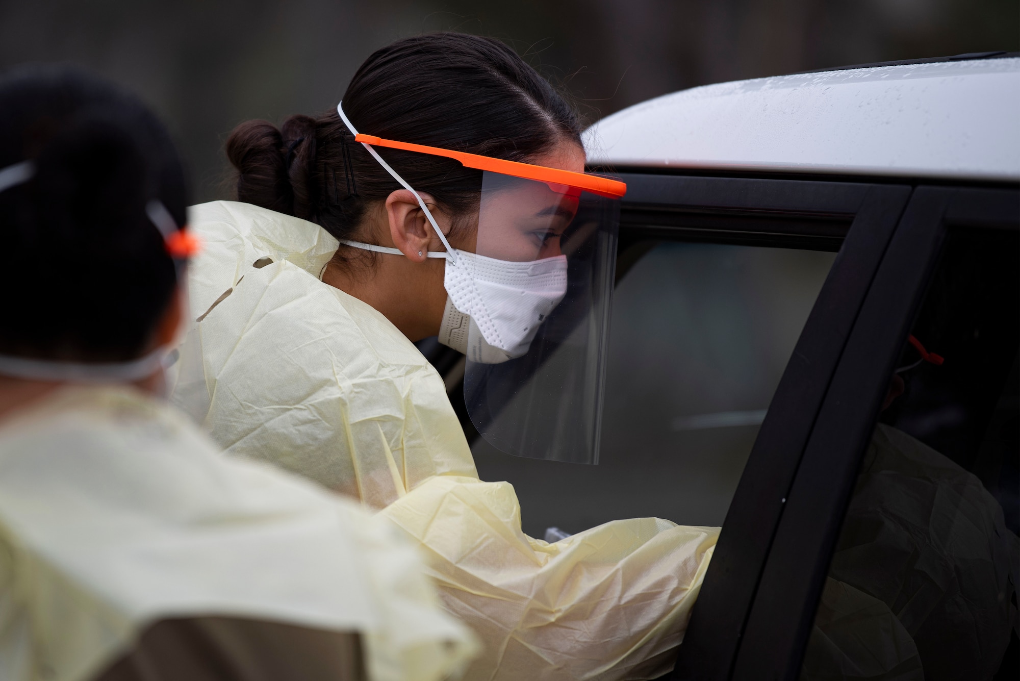 Airman Sidney Brown, 30th Medical Group medical technician, reaches through a car window to conduct a drive-through COVID-19 test July 31, 2020, at Vandenberg Air Force Base, Calif. During the COVID-19 drive-through testing, medical technicians come into contact with many potential COVID-19 carriers, so wearing proper personal protective equipment is essential. The face shield that Brown is wearing is one of many made by Maj. Jonathan Wavell, Combined Force Space Components Command targets chief, using 3-D printing at the base library.  (U.S. Air Force photo by Senior Airman Hanah Abercrombie)