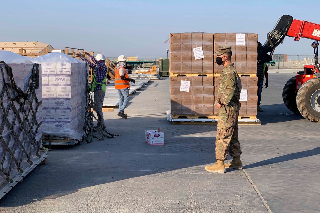 A soldier observes large cases being moved.