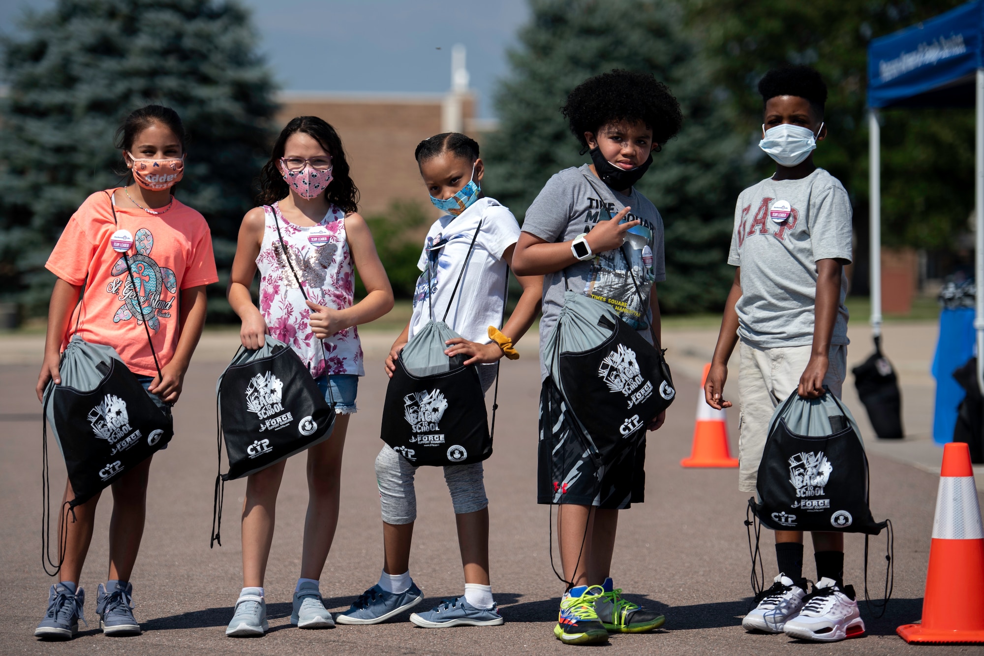 Elementary school students hand out school supplies to their fellow classmates during the School Supply Drive-By event held at the Peterson Air Force Base youth center on August 14, 2020.
