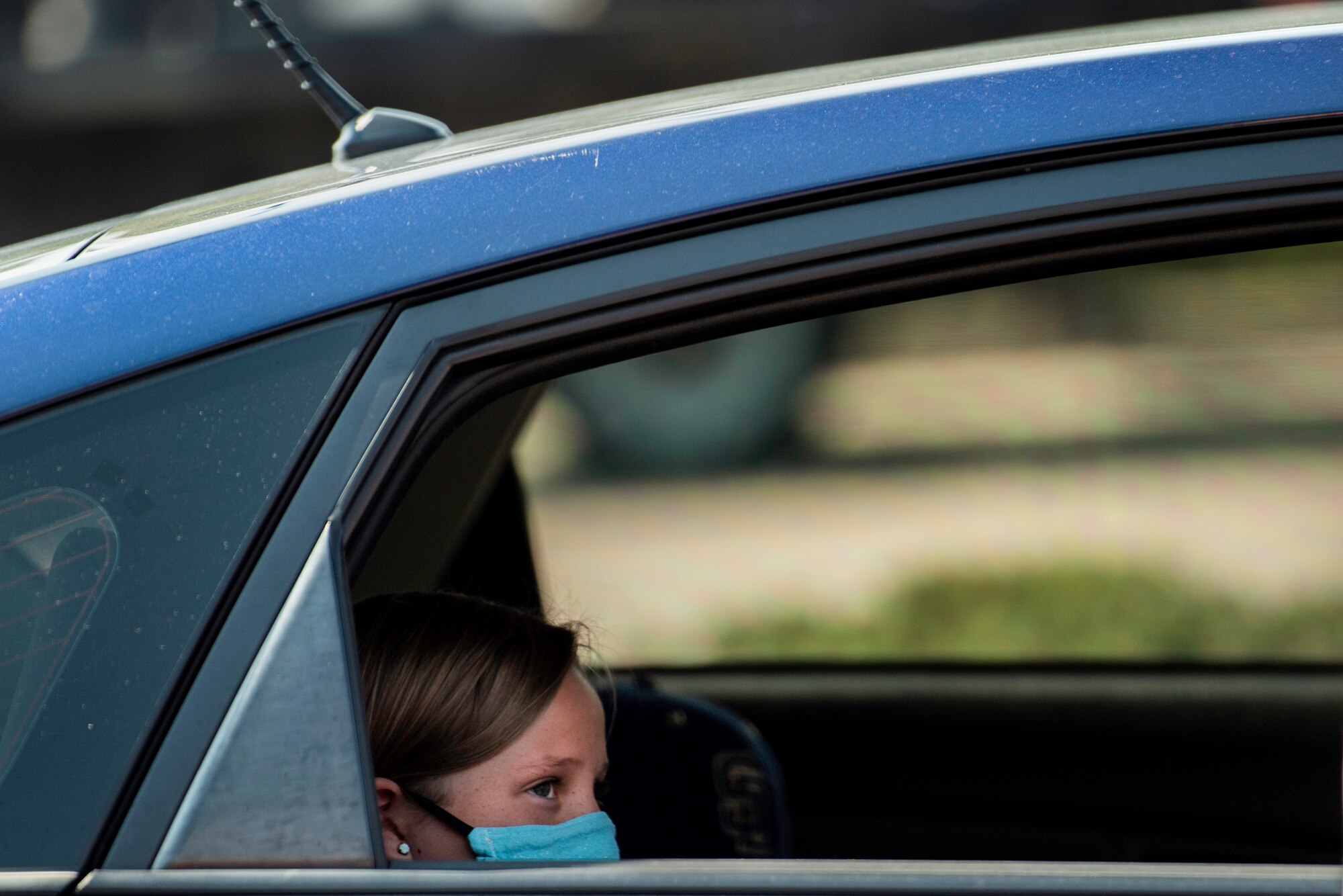 An elementary student sits in her car as her parents pick up a drawstring backpack during the School Supply Drive-By event today at the Peterson Air Force Base youth center on Aug. 14, 2020.