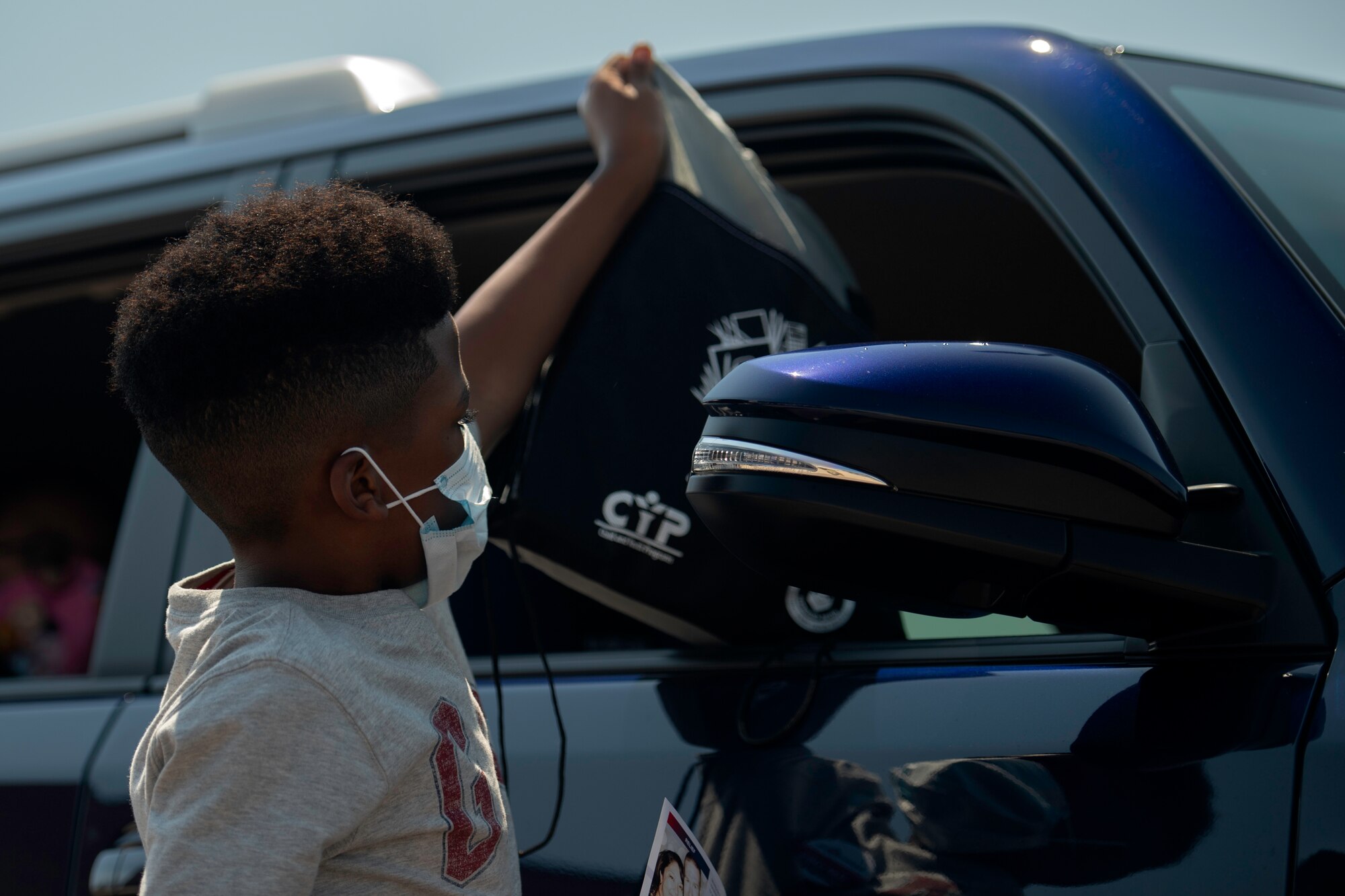 Camron Pressley, an elementary school student, hands school supplies to a family during the School Supply Drive-By at Peterson Air Force Base on Aug. 14, 2020.