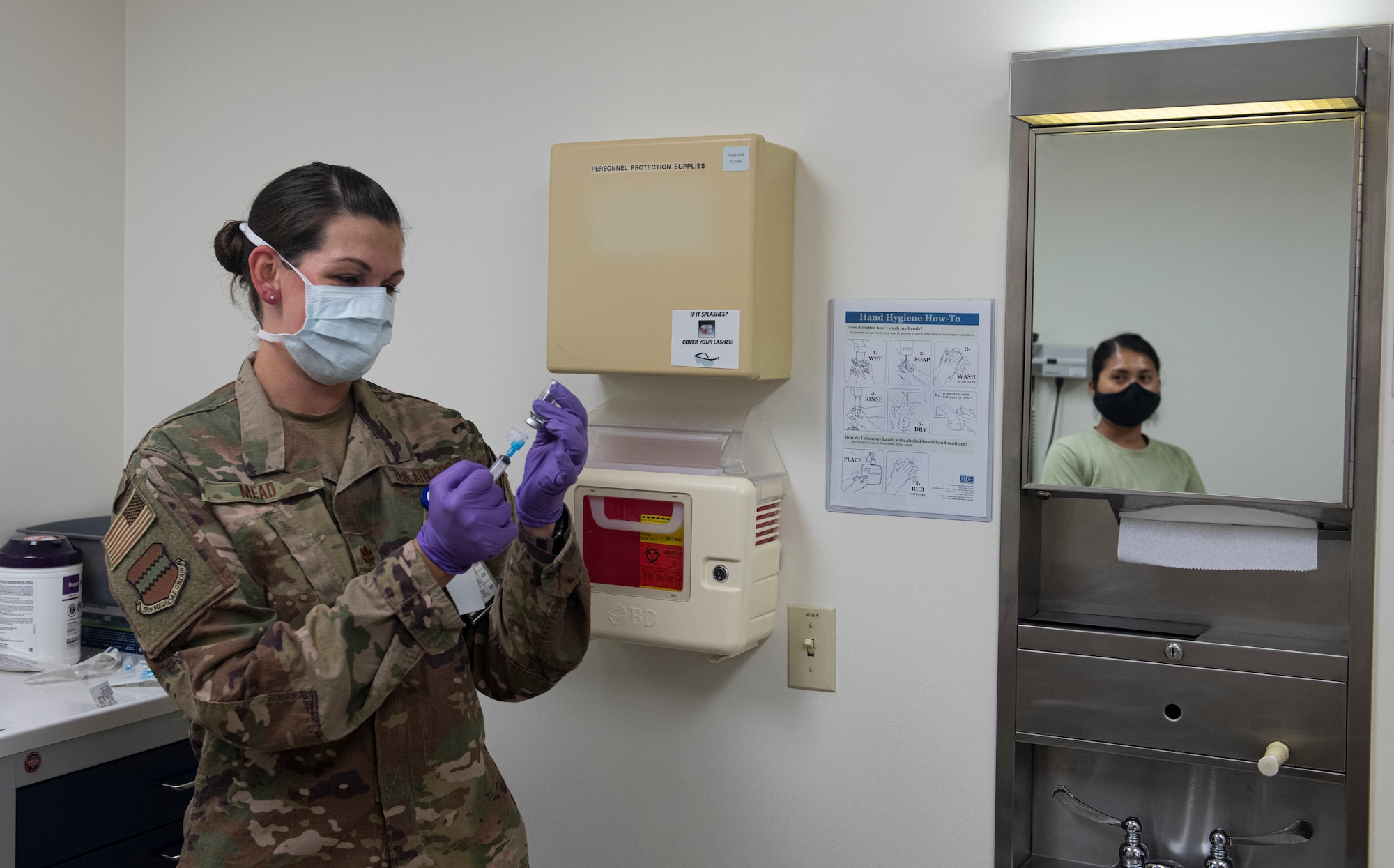 Airman prepares to give another Airman a shot.