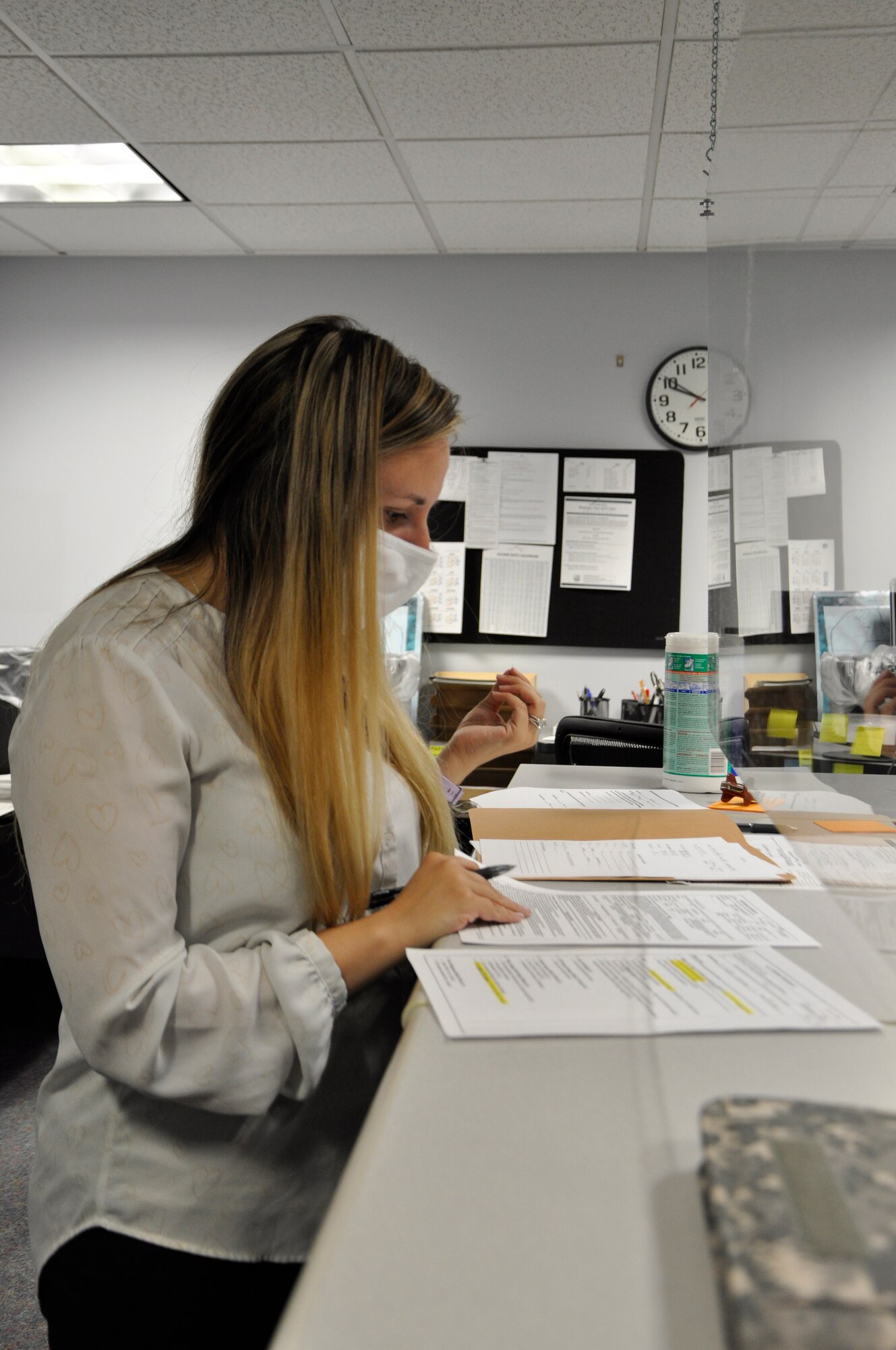 Woman reviews pay documents behind a glass shield.