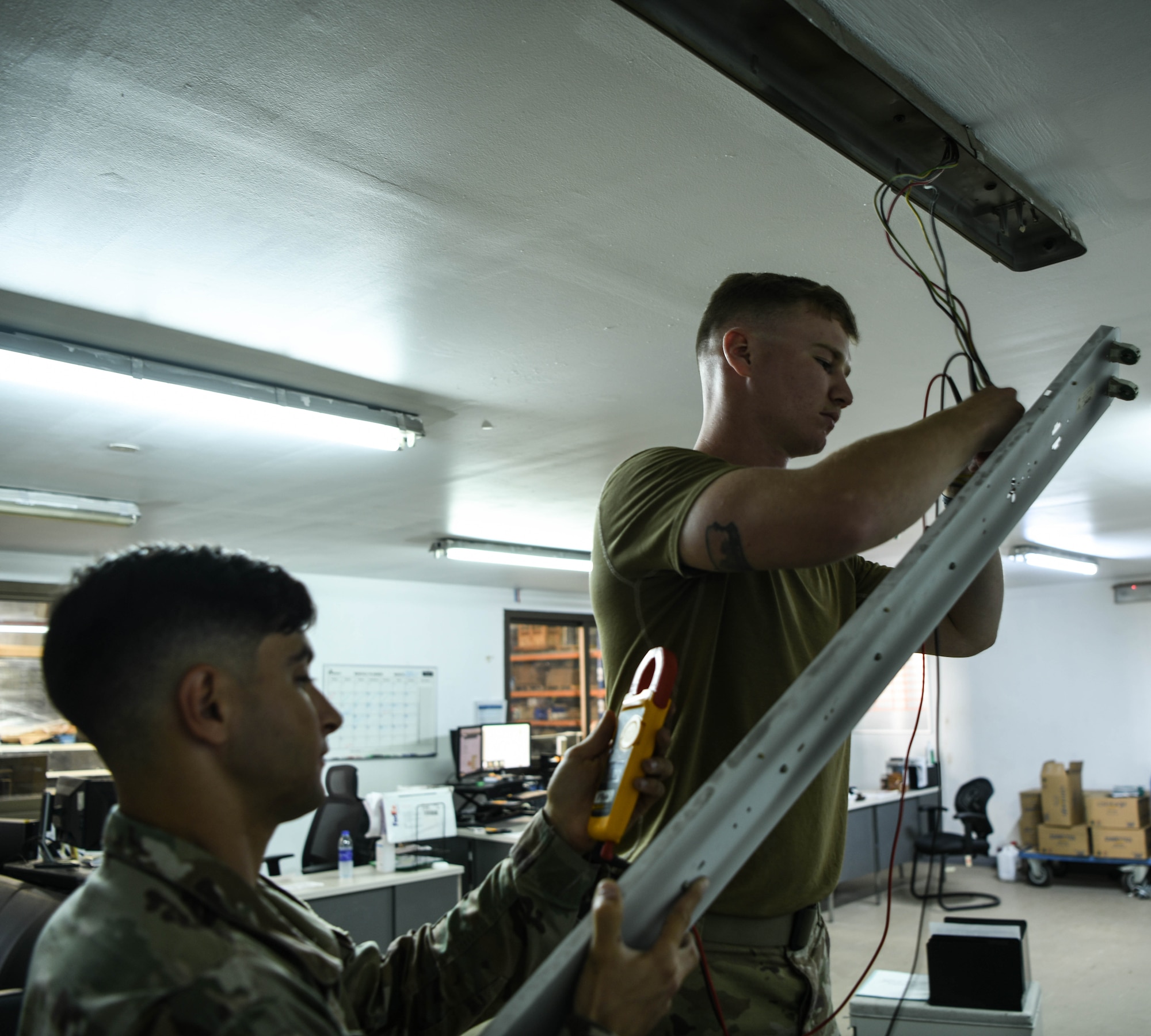 Staff Sgt. Seth Sammons (left) and Senior Airman Joshua Hancock, both members of the 380th Expeditionary Civil Engineer Squadron, repair a light fixture August 11, 2020 here.