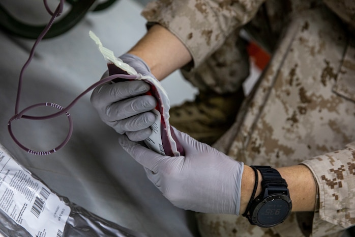 A U.S. Navy Hospital Corpsman examines a unit of blood during an Emergency Whole Blood Transfusion Training Program in Kuwait, July 30.