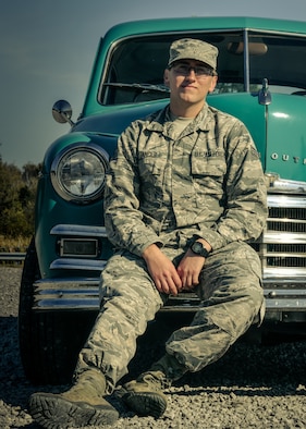 Senior Airman Noah Tancer, a public affairs specialist with the 910th Airlift Wing, sits on the front bumper of a 1949 Plymouth on October 15, 2019, at Youngstown Air Reserve Station. Tancer along with a handful of family members spent over three years restoring the car after Tancer purchased it for $1,000 upon graduating from high school.