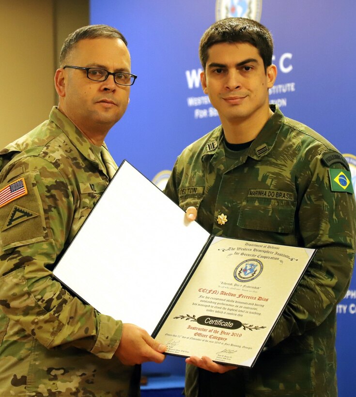 Military personnel hold a certificate.