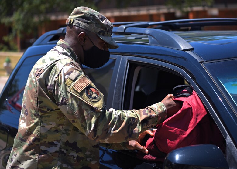 U.S. Air Force Col. James Finlayson, 17th Training Wing vice commander, gives a backpack to a military member during Operation Back to School on Goodfellow Air Force Base, Texas, Aug. 12, 2020. Finlayson and other members of Goodfellow assisted in handing out backpacks filled with supplies to families to assist with preparing children for school. (U.S. Air Force photo by Airman 1st Class Ethan Sherwood)