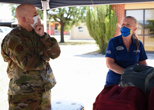 U.S. Air Force Col. Andres Nazario, 17th Training Wing commander, and 17th Force Support Squadron marketing specialist Julie Manuel, discuss base affairs while waiting for families to pick up backpacks during Operation Back to School on Goodfellow Air Force Base, Texas, Aug. 12, 2020. Nazario assisted Operation Back to School by handing out backpacks to military families at the drive-through. (U.S. Air Force photo by Airman 1st Class Ethan Sherwood)