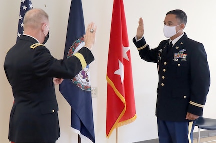 Maj. Gen. Timothy P. Williams, the adjutant general of Virginia, administers the oath of office to newly promoted Maj. Waldon W. Jue July 30, 2020, in Fairfax, Virginia. Jue is the first Army National Guard Soldier to direct commission as a cyber operations officer.