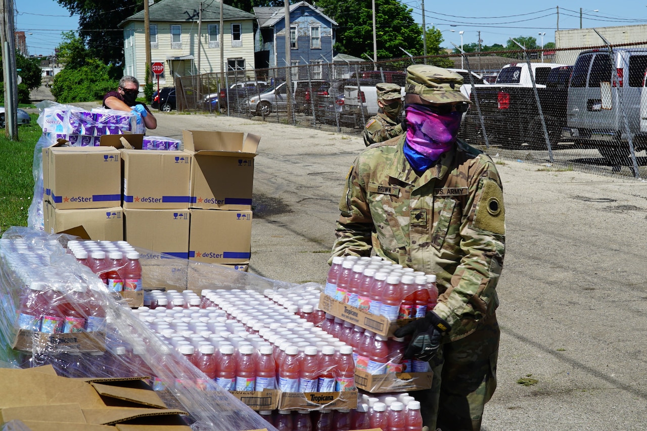 Soldiers wearing face masks load food into waiting vehicles.
