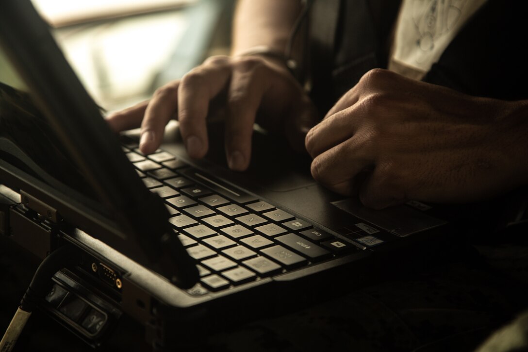 A Marine’s hands on a laptop computer’s keyboard.