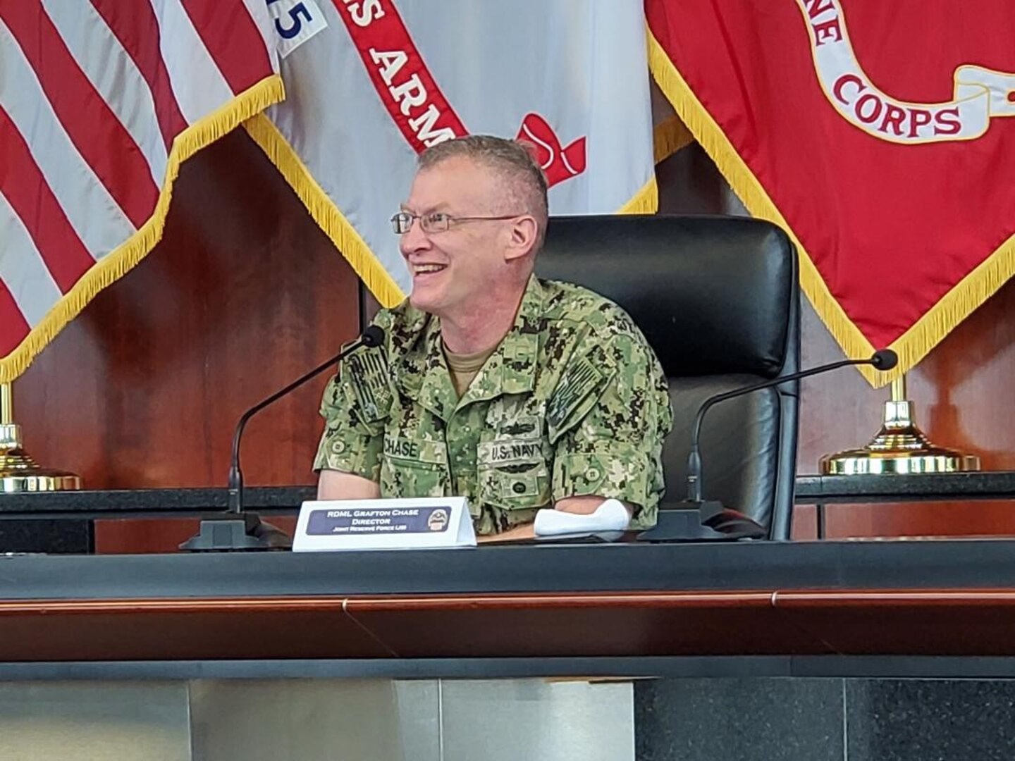 Rear Adm. Grafton Chase seated  behind a conference table