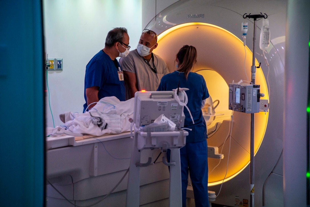 Doctors stand near an MRI machine.