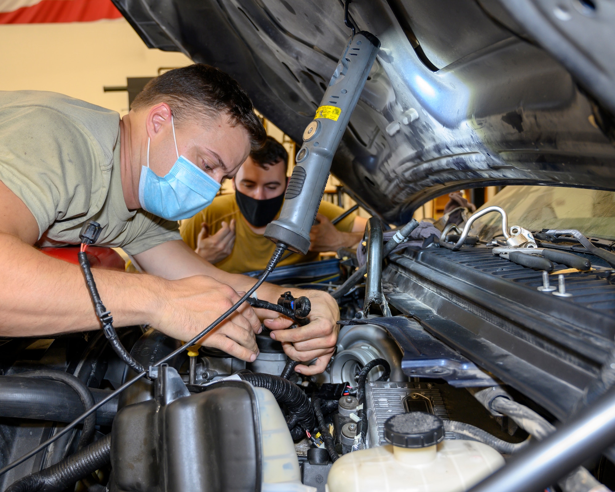Two Airmen inspect wiring in an engine as part of routine and preventative maintenance.