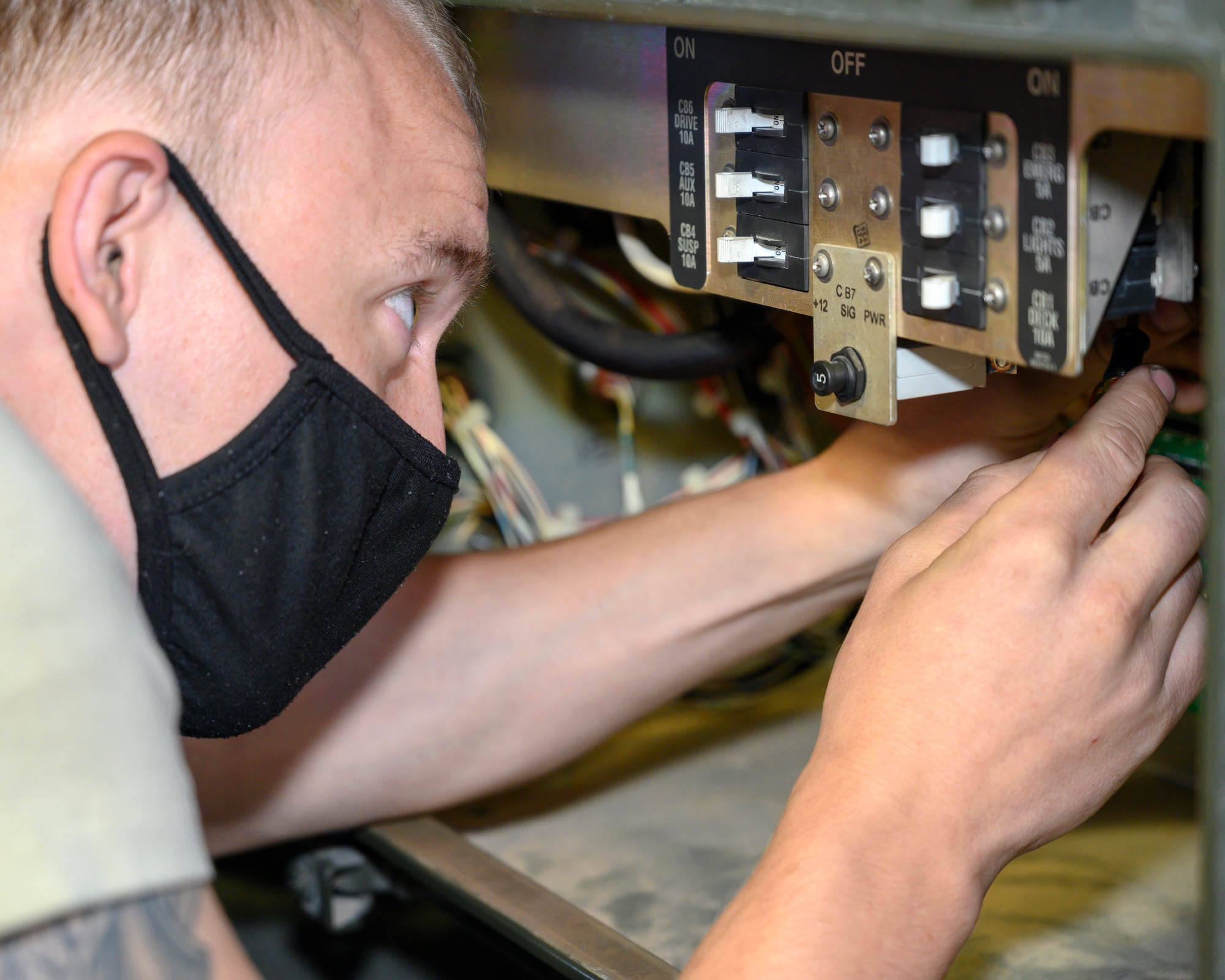 An Airman inspects the electrical system of a Tunner loader.