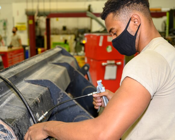 An Airman greases the joints of a special purpose heavy vehicle