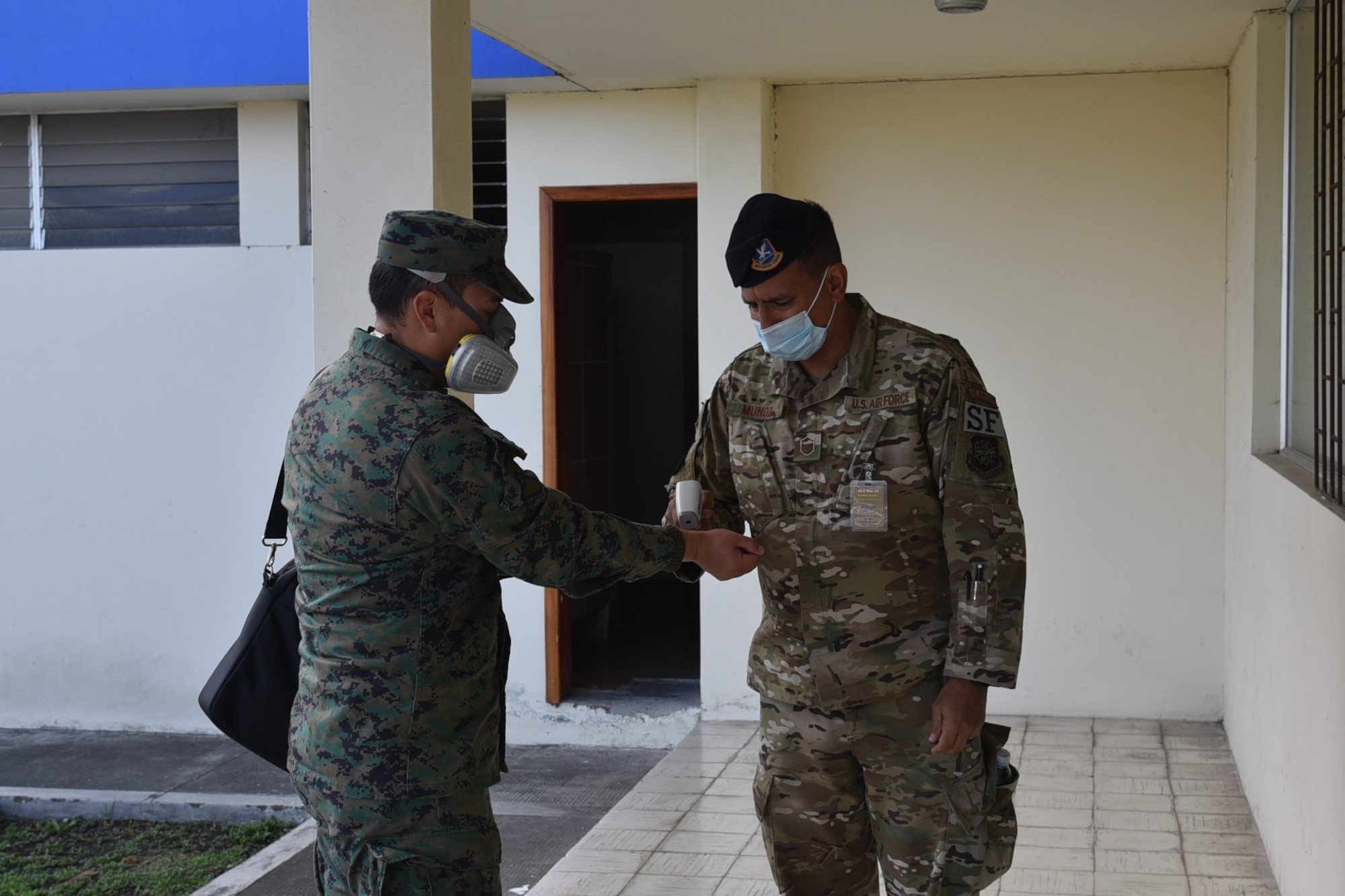 U.S. Air Force Master Sgt. Freddy Muñoz, 571st Mobility Support Advisory Squadron security forces lead air advisor, takes the temperature of Fuerza Aérea Ecuatoriana Cabo Primero Paúl Valdez as a COVID-19 precaution prior to entering the auditorium July 17, 2020, at Cotopaxi Air Force Base in Latacunga, Ecuador. (U.S. Air Force photo by Capt. Kaitlin Morones)