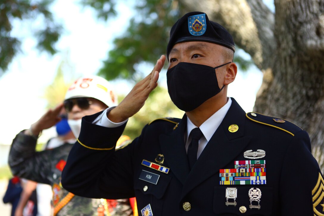 A soldier wearing a mask salutes outside.