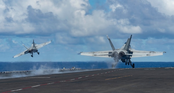 An F/A-18F Super Hornet, right, and an F/A-18E Super Hornet launch from the flight deck of USS Ronald Reagan (CVN 76).