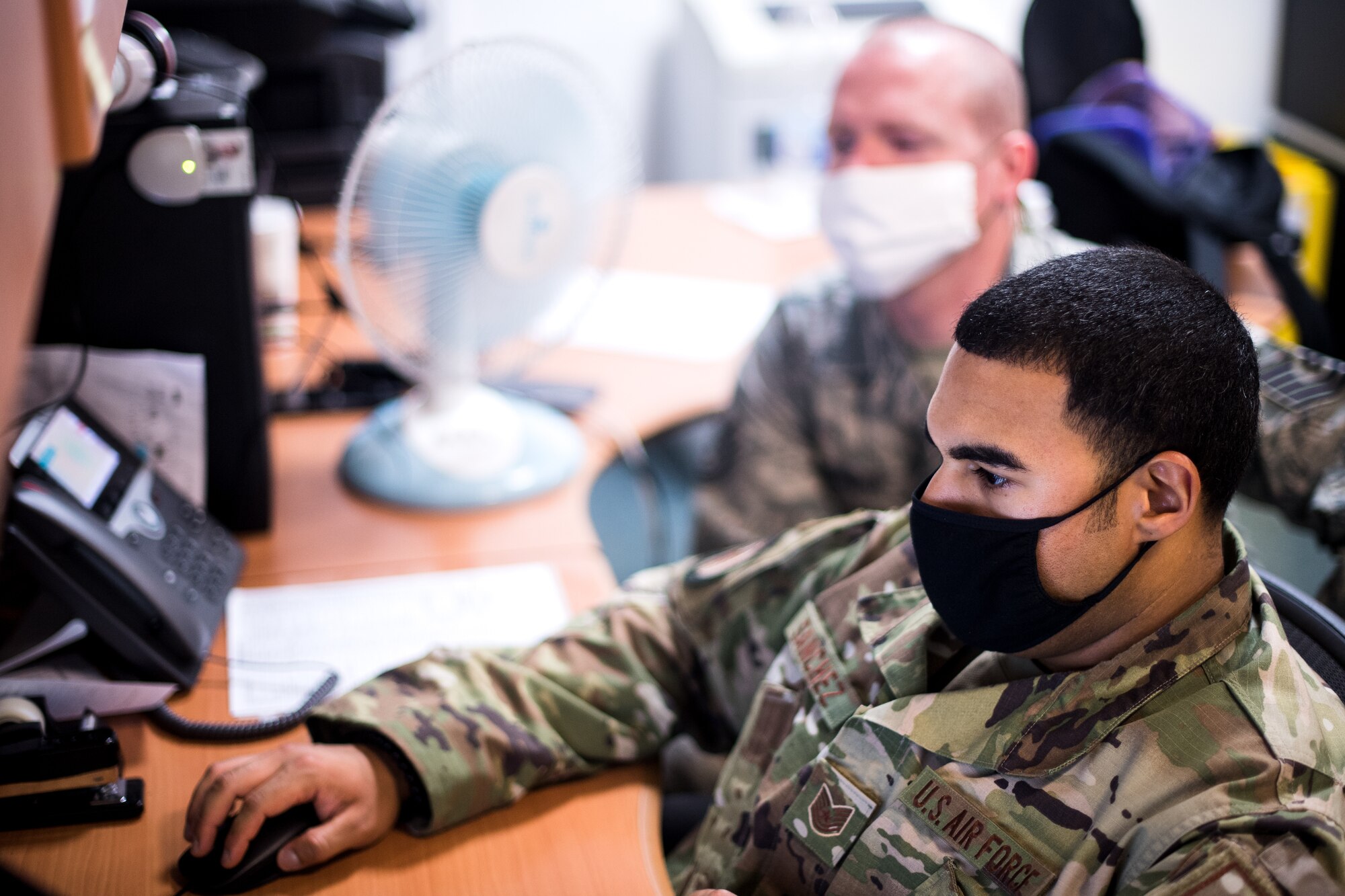 Photo of Airman assisting another Airman on a computer