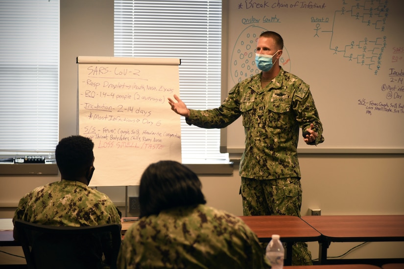 A sailor wearing a face mask teaches a course.