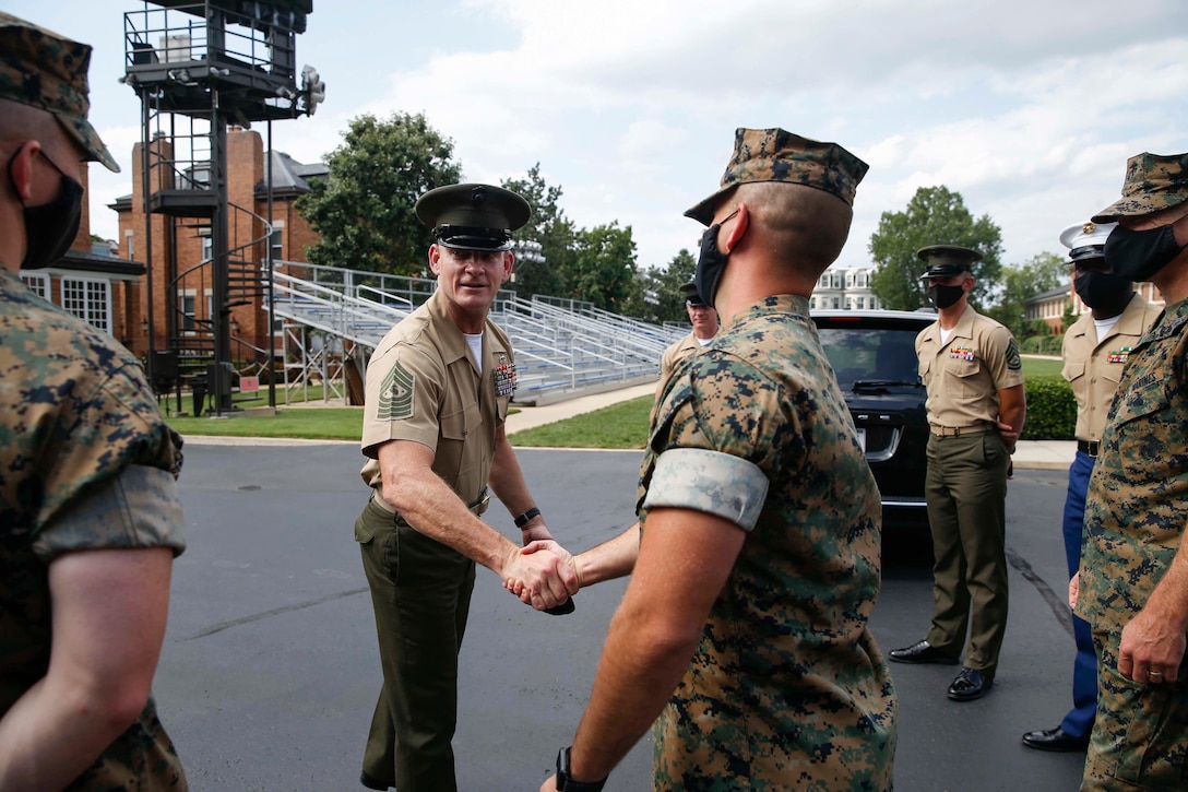 The 19th Sergeant Major of the Marine Corps, Sgt. Maj. Troy E. Black, hands a coin to Cpl. Robert Clark, a bugler from The Commandant’s Own Drum and Bugle Corps at Marine Barracks Washington, D.C., Aug. 5, 2020. The Marine was presented a coin for outstanding performance and discipline. The Drum and Bugle Corps provides music for the Commandant and Barracks commander. (U.S. Marine Corps photo by Sgt. Victoria Ross)
