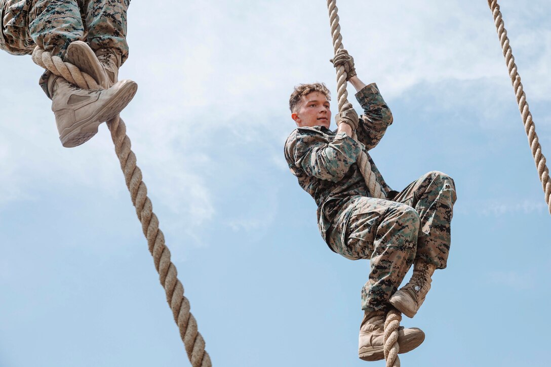 A Marine climbs a rope.